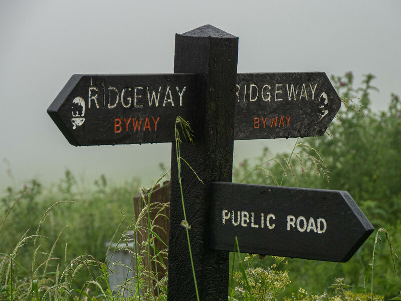 Signpost showing ridgeway byway and public road with wet grasses