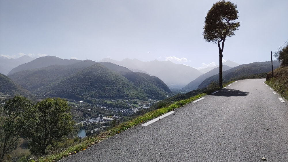 Smooth tarmac road on climbing a mountain with town in valley below.