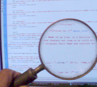 Large magnifying glass held in front of screen showing code.