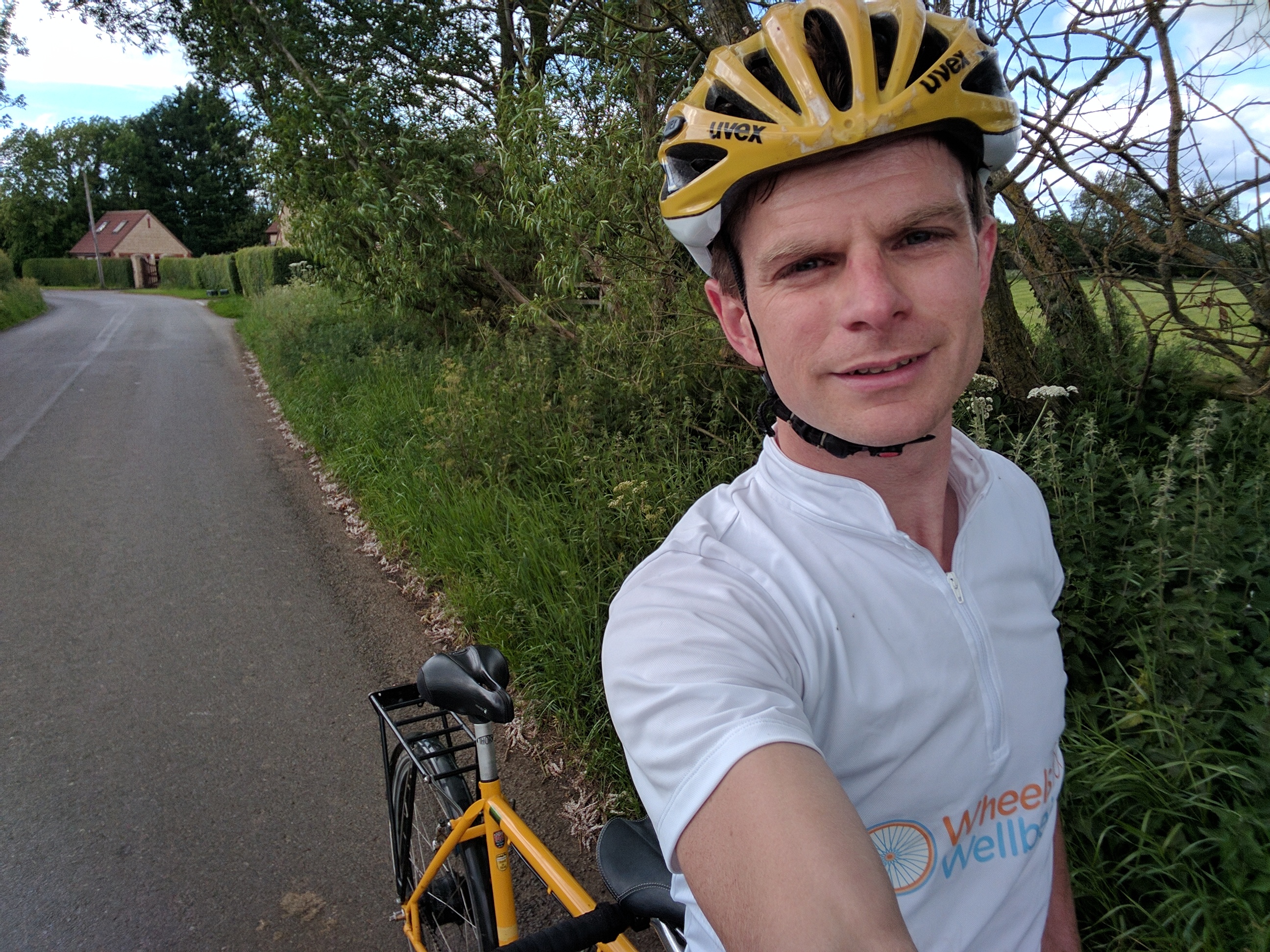 James in a white jersey with tandem in a country lane, rear seat is unoccupied.